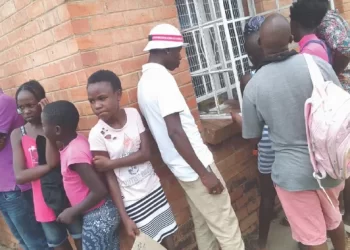Parents and pupils queue outside a window at Mthombowesizwe Primary School to purchase book covers